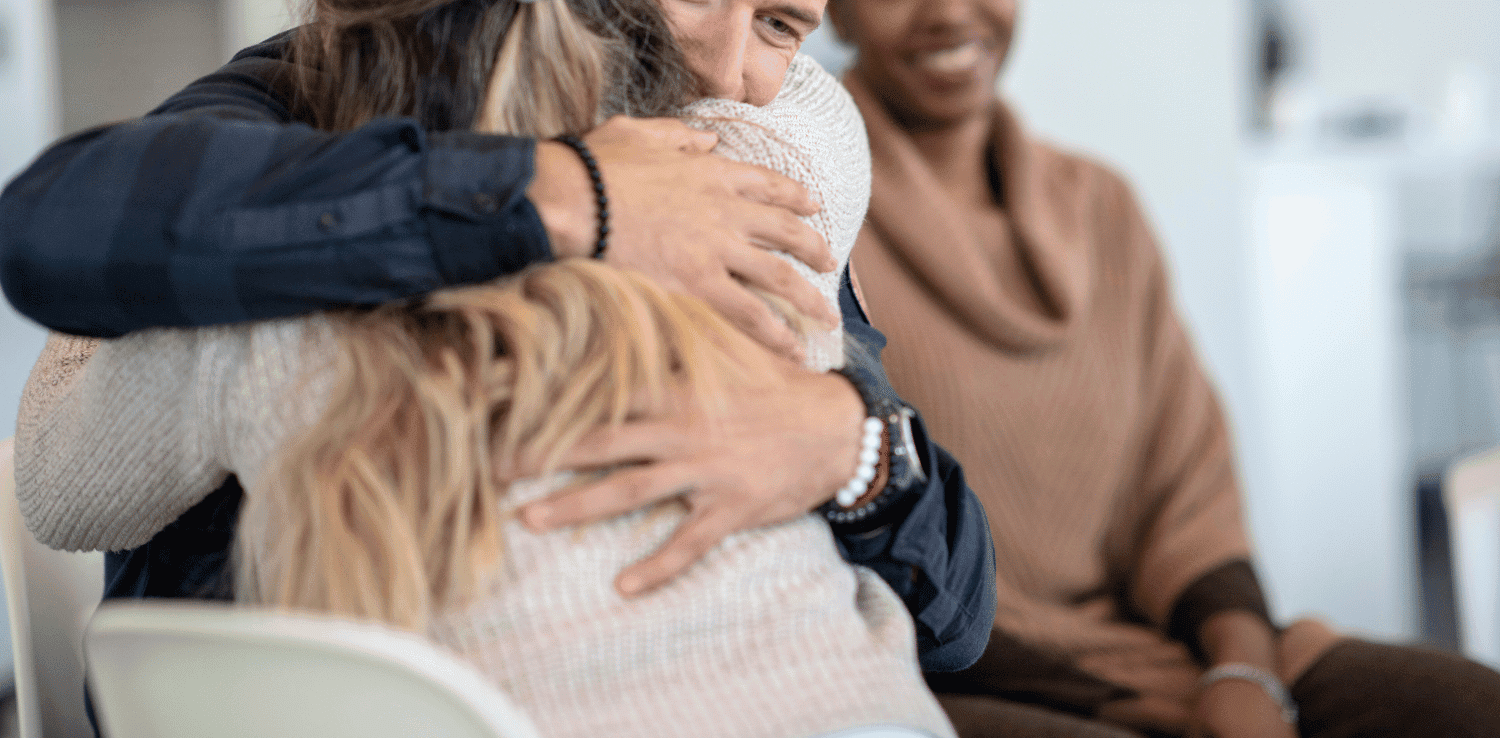 HIV support groups counselor hugging a member while another member looks on