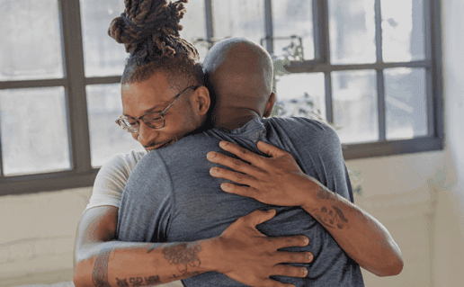 Two men hugging in a counselling session, focusing on HIV and mental health.
